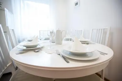 a white table with white plates and silverware on it at Apartments Grom in Bled