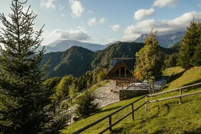 a cabin on a hill with mountains in the background at Eco Chalet Astra Montana in Tolmin