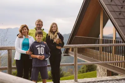 a family posing for a picture in front of a cabin at Eco Chalet Astra Montana in Tolmin