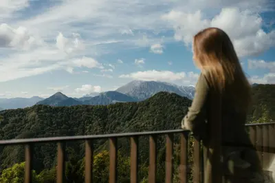 a woman standing on a balcony looking out at the mountains at Eco Chalet Astra Montana in Tolmin