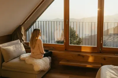 a woman sitting on a couch in a room with a window at Eco Chalet Astra Montana in Tolmin