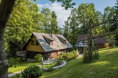 a house with a gambrel roof on a yard at Počitniška hiša Koča Dobnik in Lovrenc na Pohorju