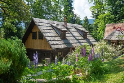 a wooden house with a shingled roof in a garden at Počitniška hiša Koča Dobnik in Lovrenc na Pohorju