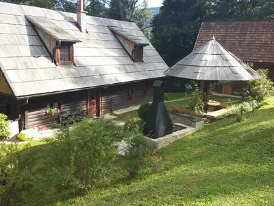 an old house with a tin roof and a garden at Počitniška hiša Koča Dobnik in Lovrenc na Pohorju