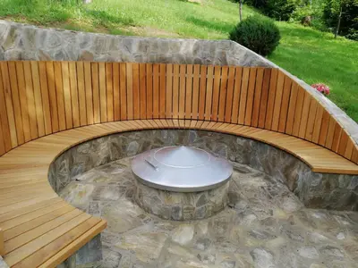 a wooden bench in a garden with a fountain at Počitniška hiša Koča Dobnik in Lovrenc na Pohorju