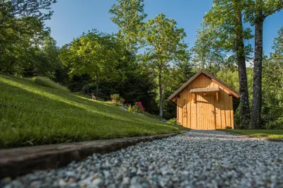 a small wooden building on a gravel road at Počitniška hiša Koča Dobnik in Lovrenc na Pohorju