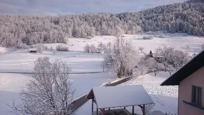 a view of a snow covered field with a house at Apartment Vrtacnik in Štefanja Gora