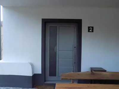 a door in a white wall with a wooden bench at Apartment Pri Ruscu in Tolmin