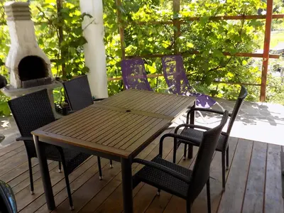 a wooden table and chairs on a deck with a fireplace at Apartment Pri Ruscu in Tolmin