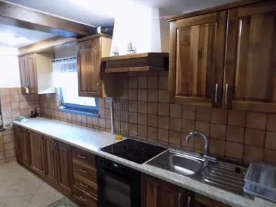 a kitchen with wooden cabinets and a stove and a sink at Apartment Pri Ruscu in Tolmin