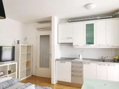 a kitchen with white cabinets and a sink at City centre studio with a balcony and free parking in Ljubljana