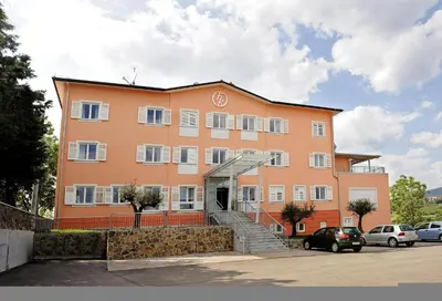 a large orange building with stairs in a parking lot at Hotel Kozana in Dobrovo