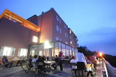 a group of people sitting at tables outside of a building at Hotel Kozana in Dobrovo