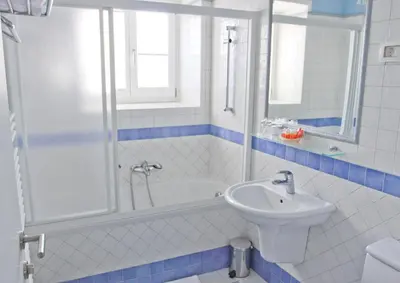 a white bathroom with a sink and a shower at Hotel Kozana in Dobrovo