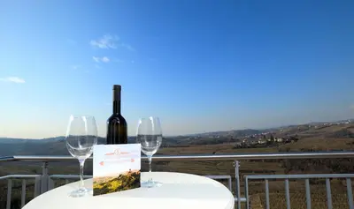 a bottle of wine sitting on a table with two glasses at Hotel Kozana in Dobrovo