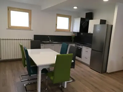 a kitchen with a white table and green chairs at Apartment Lapanja in Slappe dʼIdria