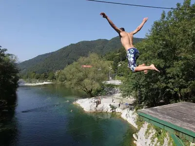 a man jumping off a bridge over a river at Apartment Lapanja in Slappe dʼIdria