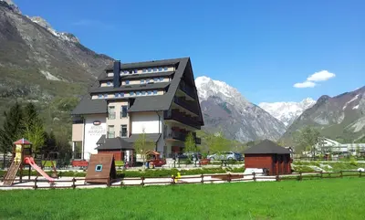 a building with a playground in front of a mountain at Hotel Mangart in Bovec