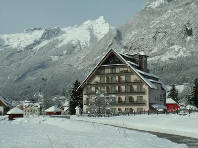 a large building in front of a mountain at Hotel Mangart in Bovec