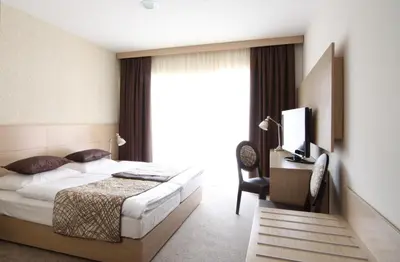 a bedroom with a bed and a desk and a television at Hotel Mangart in Bovec