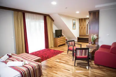 a living room with a red couch and a table at Hotel Mangart in Bovec