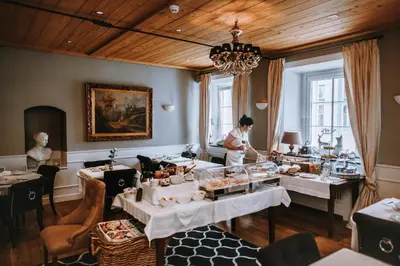 a woman standing in a room with tables with food at Lesar Hotel Angel - Member of Hip Hotels in Ljubljana