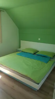 a bed with green sheets and blue pillows in a room at Holiday House Klemenčič in Bohinj