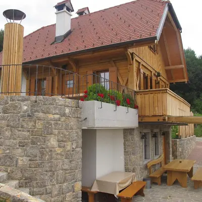 a house with a balcony and a table and benches at Zidanica Ravbar in Uršna Sela