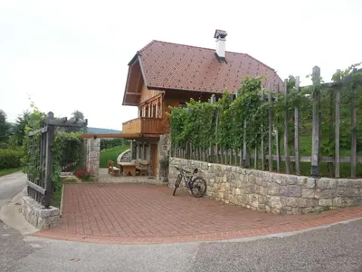 a house with a fence and a bike parked on a brick path at Zidanica Ravbar in Uršna Sela
