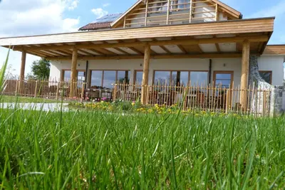 a house with a wooden roof in a field of grass at Guest House Eco Vila Mila in Rogaška Slatina