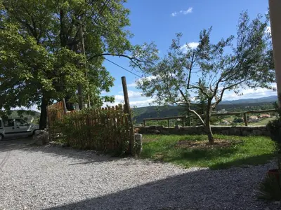 a fence with a tree next to a gravel road at Štanjelski Razgledi AR in Štanjel