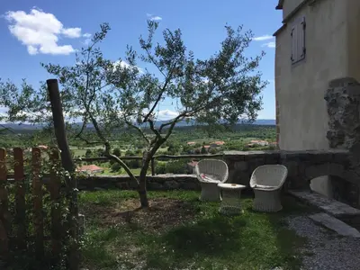 two chairs and a tree next to a building at Štanjelski Razgledi AR in Štanjel