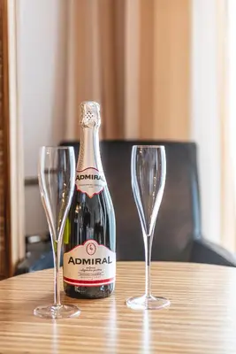a bottle of champagne and two wine glasses on a table at Casino & Hotel ADMIRAL Kozina in Kozina