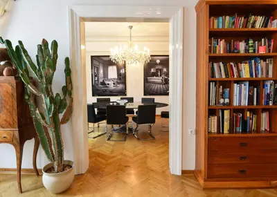 a dining room with a table and a book shelf with books at Neoclassical Luxury Apartment Ljubljana in Ljubljana