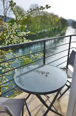 a table and chairs on a balcony overlooking a river at Guesthouse Soul in Ljubljana