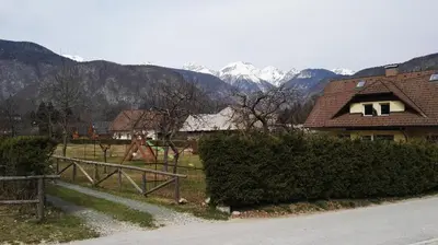 a house with a fence and mountains in the background at Apartment Šija in Bohinj