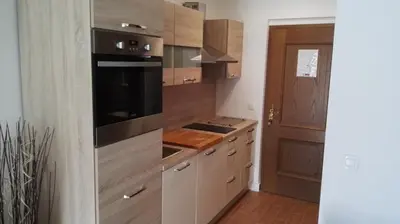 a kitchen with wooden cabinets and a stove top oven at Apartment Šija in Bohinj