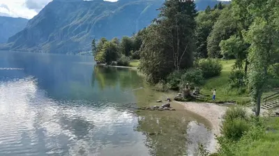 a group of people standing on the shore of a lake at Apartment Šija in Bohinj