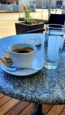 a cup of coffee on a table next to a glass of water at Hostel Novak in Novo Mesto
