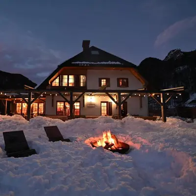 a fire pit in the snow in front of a house at Hiša Ojstrica in Solčava