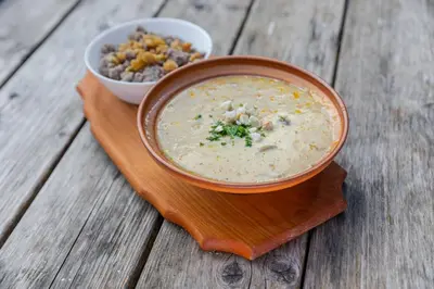 a bowl of soup on a wooden plate with a bowl of food at Hiša Ojstrica in Solčava