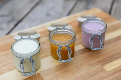 a group of four jars on a wooden cutting board at Hiša Ojstrica in Solčava
