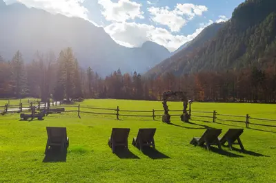 a field with chairs in the grass with mountains at Hiša Ojstrica in Solčava