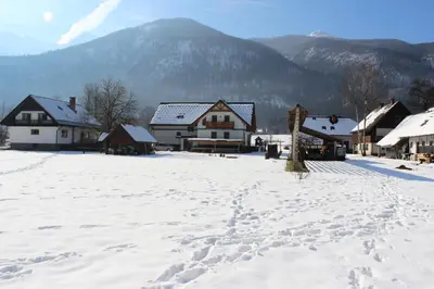 a snow covered village with houses and a mountain at Apartments Villa Dov in Bohinj