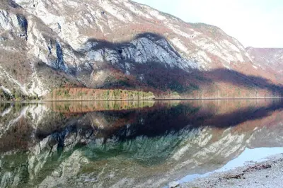 a reflection of a mountain in a body of water at Apartments Villa Dov in Bohinj