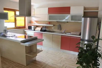 a kitchen with red and white cabinets and a sink at Apartments Villa Dov in Bohinj