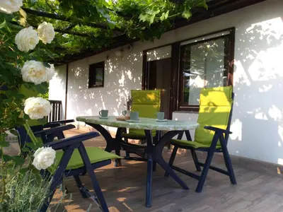 a table and chairs on a patio with flowers at Apartment Mlinarjeva domačija in Kobarid