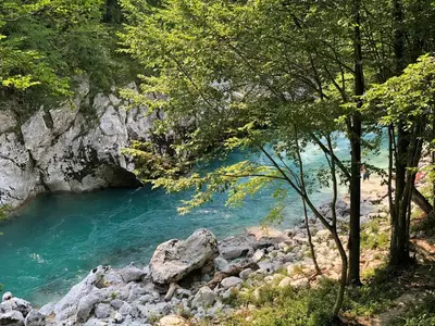 a river with blue water and some trees and rocks at Tourist Farm Žvanč in Kobarid