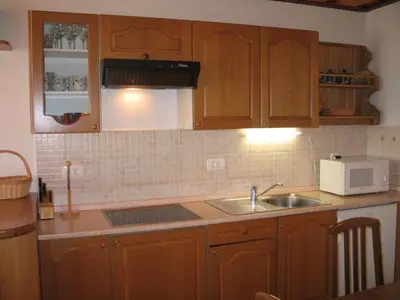 a kitchen with wooden cabinets and a sink and a microwave at Tourist Farm Žvanč in Kobarid