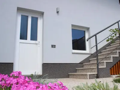 a white door on a house with pink flowers at Apartment Pri nama in Bovec